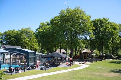 Mensen op stoelen rondom het buitenbad van vakantiepark Camping de Norgerberg