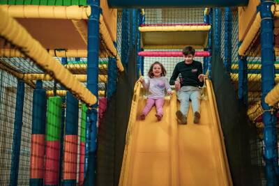 Twee kinderen op de glijbaan van de indoor speeltuin op vakantiepark Europarcs de Achterhoek