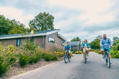 Gezin fietst tussen vakantiehuizen op vakantiepark EuroParcs Zuiderzee