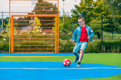 Jongen aan het voetballen op het speelveld op vakantiepark EuroParcs Zuiderzee