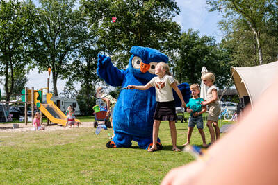 Mascotte Cobus de uil van Kampeerdorp de Zandstuve met kinderen in de speeltuin