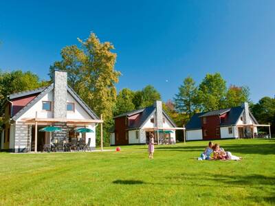 Grasveld met een gezin voor enkele vakantiehuizen op vakantiepark Landal Hochwald