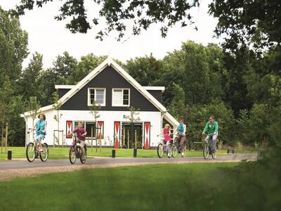 Een gezin op de fiets voor een vakantiehuis op vakantiepark Landal Resort Haamstede