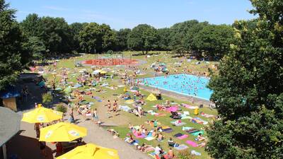 Luchtfoto van het buitenbad met ligweide van vakantiepark Molecaten Bosbad Hoeven