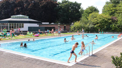 Mensen aan het zwemmen in het buitenbad van vakantiepark Molecaten Park Landgoed Ginkelduin