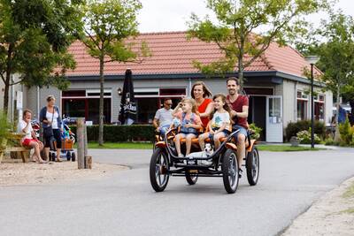 Mensen op een grote familiefiets op vakantiepark RCN Toppershoedje