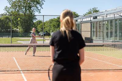 Mensen aan het tennissen op de tennisbaan van Roompot Vakantiepark Callassande