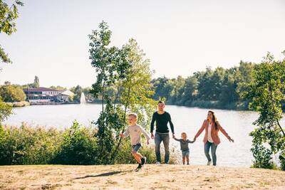 Een gezin wandelt op het strand van het recreatiemeer op Roompot Vakantiepark Weerterbergen
