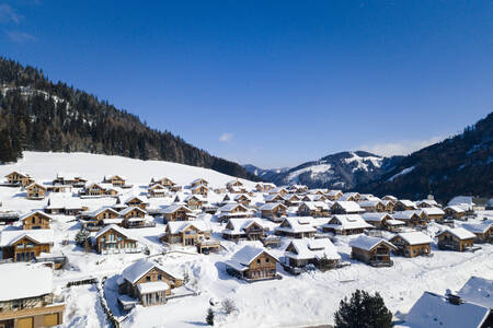 Luchtfoto van vrijstaande vakantiehuizen in de sneeuw op Alps Resorts Almdorf Hohentauern