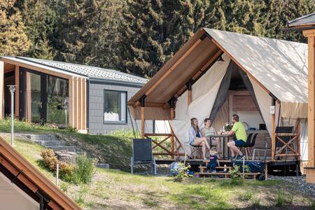 Gezin op het terras bij een glamping tent op Alps Resorts Chalets en Glamping Nassfeld