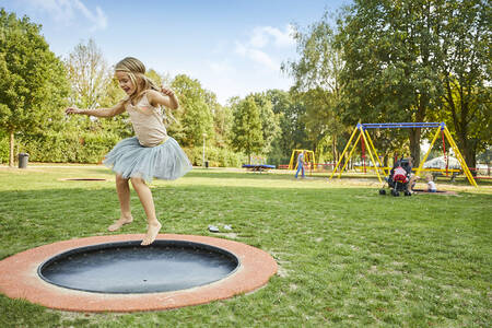 Meisje springt op een trampoline in de grote speeltuin van Buitenhof de Leistert