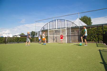 Kinderen aan het voetballen op het voetbalveld van vakantiepark Camping Zonneweelde