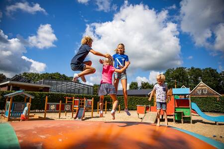 Kinderen springen op de airtrampoline in de speeltuin van camping De Witte Berg