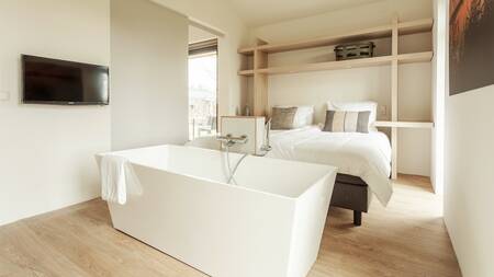 Slaapkamer met bad in een vakantiehuis op Dutchen Villapark Suitelodges Gooilanden