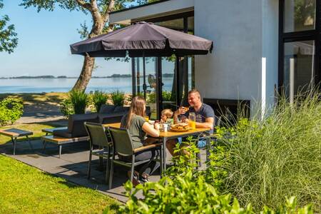 Gezin aan het eten in de tuin van een vakantiehuis op vakantiepark Europarcs Bad Hoophuizen