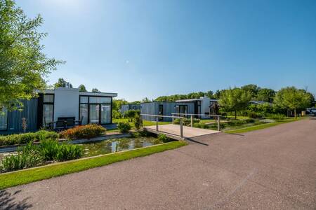 Vakantiehuizen aan een sloot met een brug op vakantiepark EuroParcs Bad MeerSee