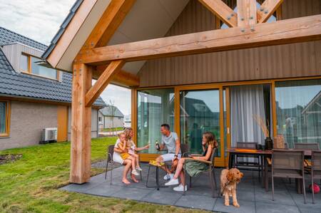 Gezin op het overdekte terras van een vakantiewoning op vakantiepark EuroParcs Cadzand