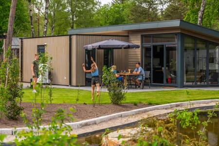 Gezin in de tuin van een chalet op vakantiepark EuroParcs De Hooge Veluwe