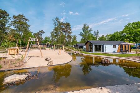 Speeltuin naast water en vakantiehuizen op vakantiepark EuroParcs De Hooge Veluwe
