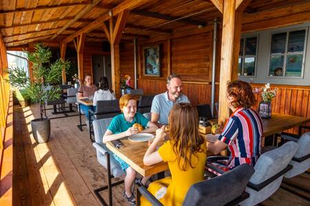 Mensen op het terras van het restaurant op vakantiepark EuroParcs De IJssel Eilanden