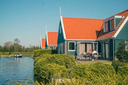 Mensen in de tuin van een vrijstaand vakantiehuis aan het water op vakantiepark EuroParcs De Rijp