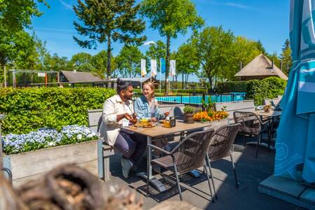 Stel eet op het terras van het restaurant op vakantiepark EuroParcs De Wije Werelt