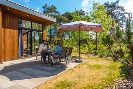 Stel aan tafel in de tuin van een vakantiehuis op vakantiepark EuroParcs De Wije Werelt