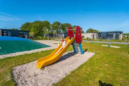 Kind op de glijbaan in de speeltuin van vakantiepark EuroParcs Enkhuizer Strand