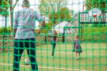 Gezin aan het voetballen op het multifunctionele speelveld van vakantiepark EuroParcs Gulperberg