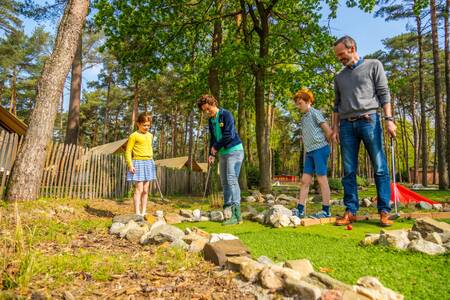 Gezin aan het golfen op de minigolfbaan van vakantiepark EuroParcs Hoge Kempen