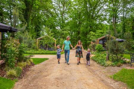 Gezin wandelt tussen de vakantiehuizen op vakantiepark EuroParcs Maasduinen