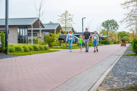 Gezin wandelt tussen chalets op vakantiepark EuroParcs Markermeer