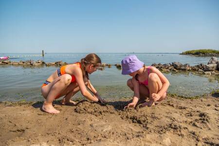 Kinderen spelen in het zand op het strand bij vakantiepark EuroParcs Poort van Amsterdam