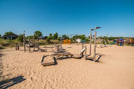 Speeltoestellen in een grote speeltuin in het zand op vakantiepark EuroParcs Poort van Zeeland