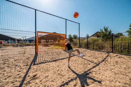 Jongen aan het voetballen op het sportveld op vakantiepark EuroParcs Poort van Zeeland