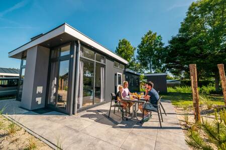 Gezin aan het eten in de tuin van een vakantiehuis op vakantiepark EuroParcs Poort van Zeeland