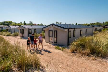 Gezin wandelt tussen vakantiehuizen op vakantiepark EuroParcs Poort van Zeeland