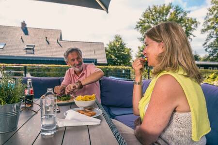 Stel aan het eten op het terras van de snackbar op vakantiepark EuroParcs Reestervallei