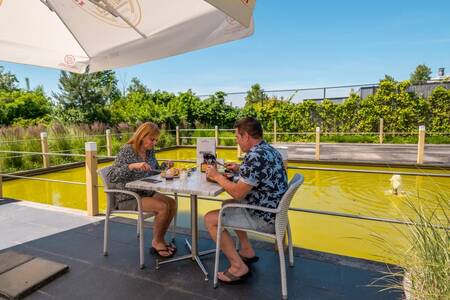 Stel eet op het terras van het restaurant van vakantiepark EuroParcs Schoneveld