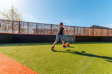 Kind aan het voetballen op het speelveld van vakantiepark EuroParcs Veluwemeer