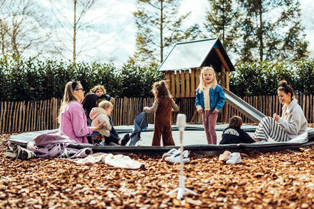 2 vrouwen met kinderen op de trampoline in de speeltuin op vakantiepark Het Wylde Pad