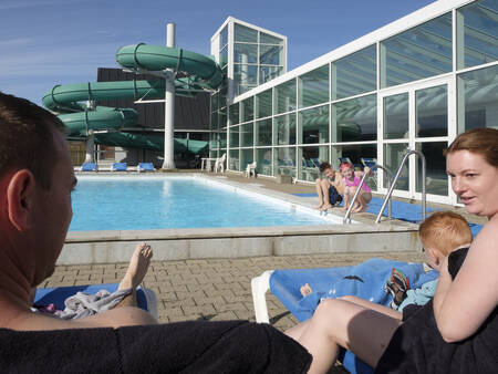 Gezin op ligstoelen bij het buitenbad op vakantiepark Landal Beach Park Grønhøj Strand