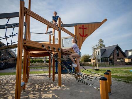 Kinderen klimmen op een speeltoestel in een speeltuin op vakantiepark Landal Berger Duinen