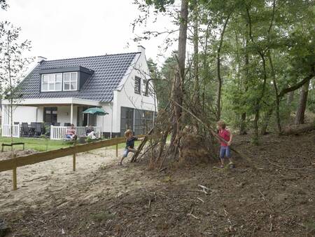 Kinderen bouwen een hut in het bos naast een vakantiehuis op vakantiepark Landal De Vers