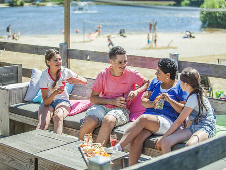 Gezin op een terras bij het natuurbad op vakantiepark Landal Domein de Schatberg