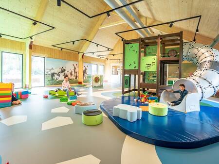 Kind glijdt van de glijbaan in de indoorspeeltuin op vakantiepark Landal Elfstedenhart