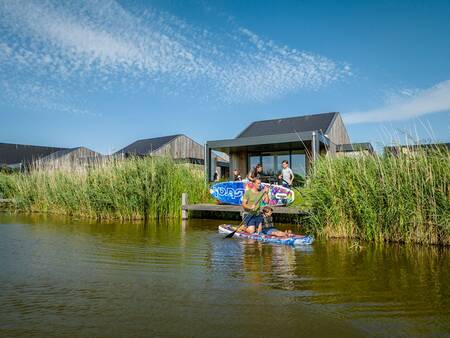 Gezin met sup boards op een steiger bij een vakantiehuis op vakantiepark Landal Elfstedenhart