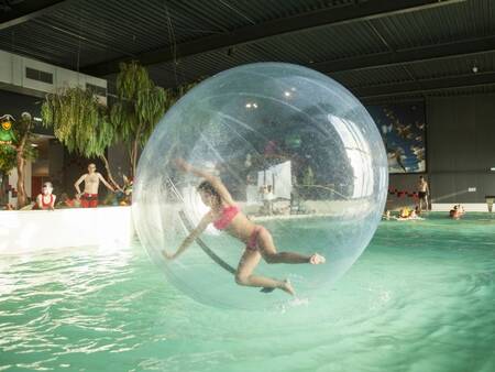Meisje in een grote bal in het zwembad van vakantiepark Landal Esonstad