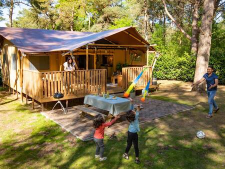 Gezin speelt bij hun safaritent op vakantiepark Landal Gooise Heide