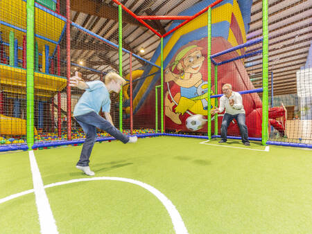 Vader en zoon voetballen in het indoorspeelparadijs van vakantiepark Landal Hochwald